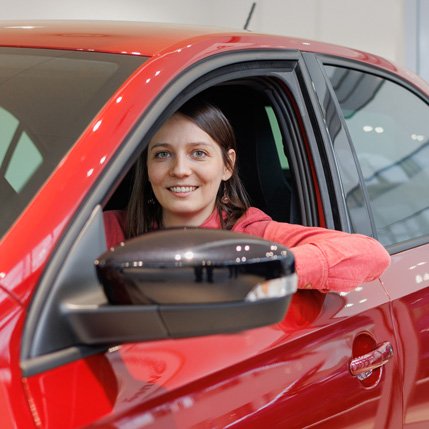 Mujer sonriente en auto rojo
