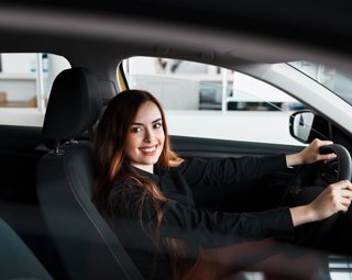 Mujer sonriente manejando vehículo oscuro
